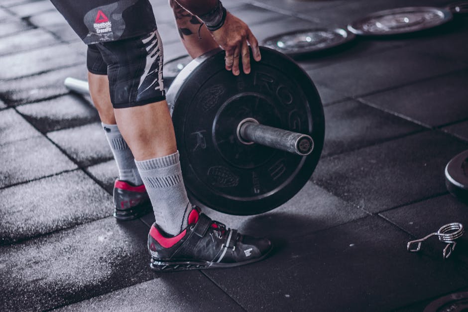 A focused man lifting a heavy barbell during weightlifting exercise in a gym.