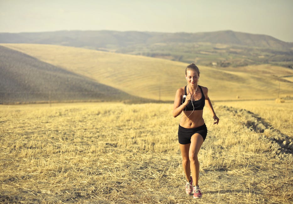 Powerful young female athlete in activewear running along hill on background of mountainous landscape